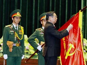 Thường trực Ban Bí thư Lê Hồng Anh gắn danh hiệu Anh hùng lực lượng vũ trang nhân dân lên lá cờ truyền thống của Văn phòng TW Cục miền Nam. (Ảnh: Thế Anh/TTXVN)