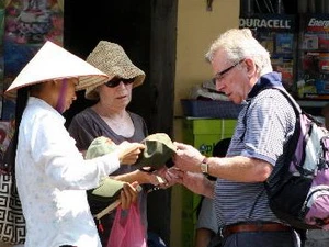 Du khách nước ngoài mua một món đồ lưu niệm tại phố cổ Hà Nội. (Ảnh: Trần Việt/TTXVN)