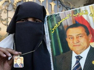 Một người ủng hộ cựu Tổng thống Hosni Mubarak cầm ảnh của ông bên ngoài bệnh viện nơi ông điều trị ở Cairo. (Nguồn: AFP/TTXVN)