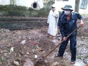 Người dân đào một khu vực chôn các thùng thuốc trừ sâu đã hết hạn. (Ảnh: Trịnh Duy Hưng/TTXVN)