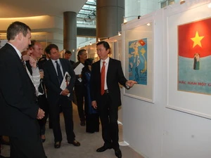Đại sứ Phạm Sanh Châu giới thiệu nội dung các bức tranh với khách tham quan.(Ảnh: Thái Văn/Vietnam+)