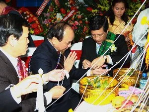 Đại sứ Lào tại Việt Nam buộc chỉ lên cổ tay Phó Thủ tướng Nguyễn Xuân Phúc tại lễ buộc chỉ cổ tay truyền thống của nhân dân các bộ tộc Lào. (Ảnh: Doãn Tấn/TTXVN)