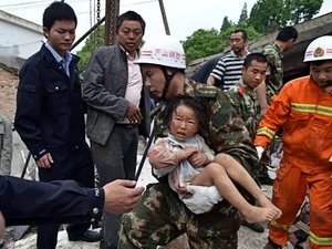 Nhân viên cứu hộ đưa một em bé ra khỏi ngôi nhà sập sau trận động đất ở tỉnh Tứ Xuyên. (Nguồn: THX/TTXVN)