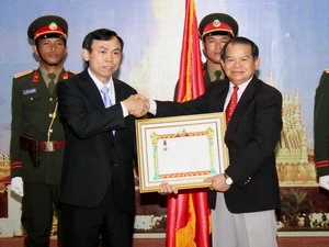 Ông Soukan Mahalath trao tặng Huân chương cho ông Trần Văn Thực. (Ảnh: Hoàng Chương/Vietnam+)