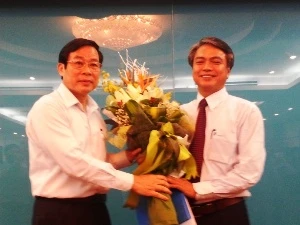 Ông Trần Mạnh Hùng (phải) nhận hoa từ Bộ trưởng Nguyễn Bắc Son. (Ảnh: T.H/Vietnam+)