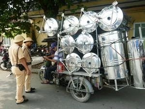 Lực lượng Cảnh sát giao thông tiến hành kiểm tra đối với xe ba bánh tự chế chở hàng cồng kềnh trên đường Trần Nhật Duật. (Ảnh: Việt Hùng/Vietnam+)