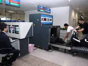 Nhân viên an ninh kiểm tra hành lý của khách qua sân bay. (Ảnh: Hoàng Hải/TTXVN)