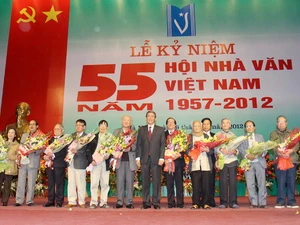 Đồng chí Đinh Thế Huynh tặng hoa chúc mừng lãnh đạo Hội Nhà văn Việt Nam qua các thời kỳ. (Ảnh: Thanh Tùng/TTXVN)