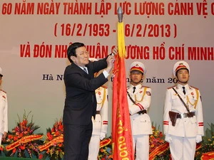 Chủ tịch nước Trương Tấn Sang gắn Huân chương Hồ Chí Minh lên Cờ truyền thống của Lực lượng Cảnh vệ Công an nhân dân. (Ảnh: Nguyễn Khang/TTXVN)