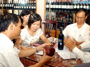 Kiểm tra nhãn mác rượu và phát hiện rượu giả ở một nhà hàng ăn. (Ảnh: Hữu Oai/TTXVN)