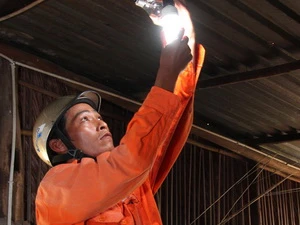 Lắp bóng đèn tiết kiệm điện cho hộ dân Kh'mer. (Ảnh: Ngọc Hà/TTXVN)
