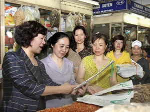 Vận động bà con tiểu thương chợ Đồng Xuân sử dụng túi giấy. (Ảnh: Thái Bình/TTXVN)
