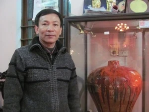 Nghệ nhân Trần Độ bên cạnh sản phẩm gốm men đỏ, một loại men hỏa biến cực khó tạo. (Ảnh: Phạm Mai/Vietnam)