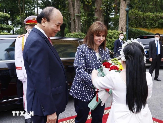 Thiếu nhi Hà Nội tặng hoa Tổng thống Hy Lạp Katerina Sakellaropoulou tại lễ đón. (Ảnh: Thống Nhất/TTXVN)