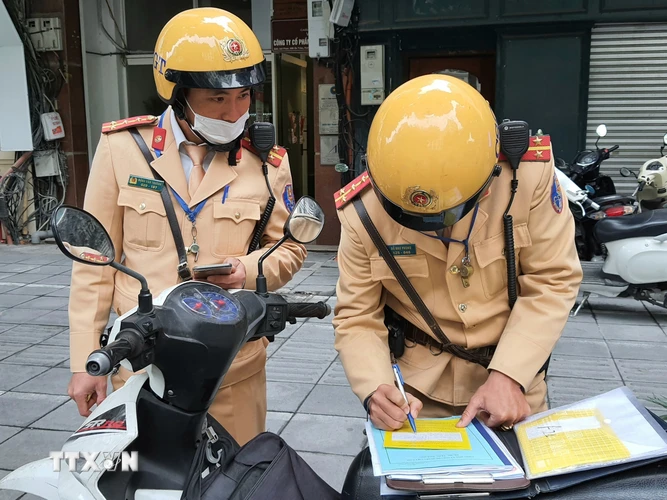 Cảnh sát giao thông viết biên bản phạt nguội đối với phương tiện dừng, đỗ trái phép trên phố Bà Triệu. (Ảnh: Doãn Tấn/TTXVN)