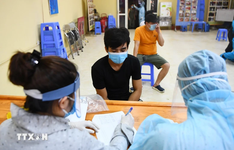 Các tiểu thương chợ Long Biên khai báo y tế trước khi lấy mẫu xét nghiệm. (Ảnh: Thành Đạt/TTXVN)