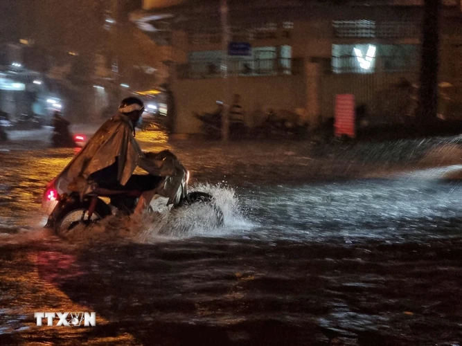 Người dân vượt làn nước ngập trên đường Ung Văn Khiêm, quận Bình Thạnh. (Ảnh: Hồng Giang/TTXVN)