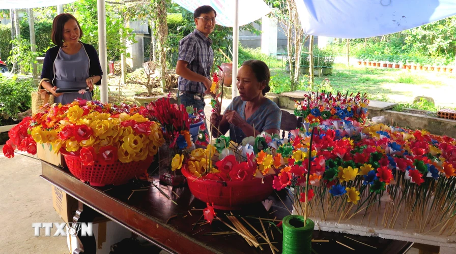 Nhiều du khách đến với làng nghề để tìm hiểu và trải nghiệm các công đoạn làm hoa. (Ảnh: Tường Vi/TTXVN)