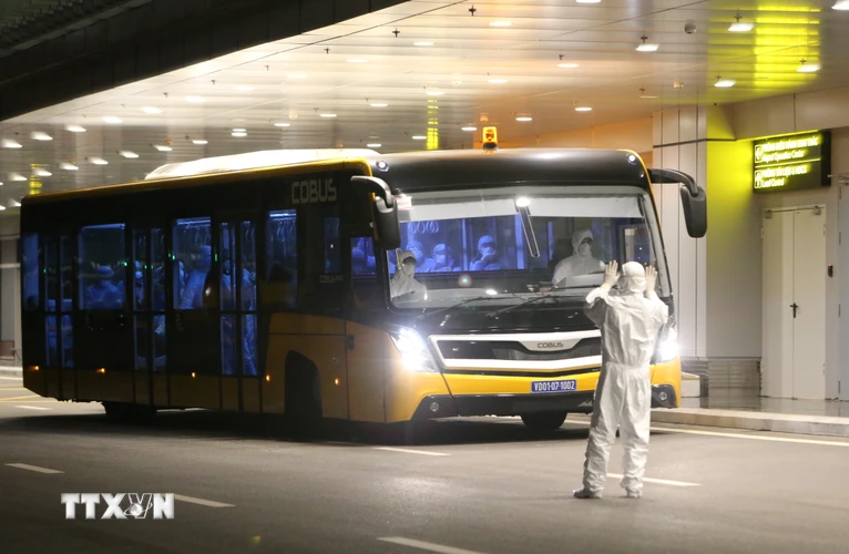 Xe buýt chở 30 công dân Việt Nam từ máy bay vào khu vực khử trùng và làm thủ tục nhập cảnh. (Ảnh: Dương Giang/TTXVN)