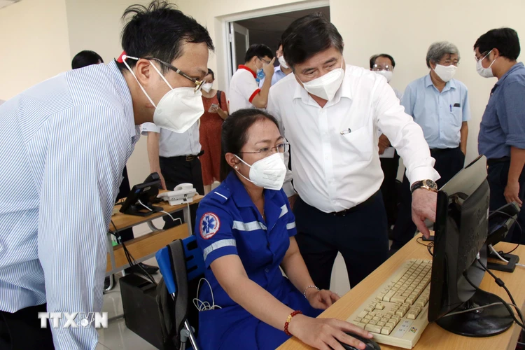 Chủ tịch UBND Thành phố Hồ Chí Minh Nguyễn Thành Phong trao đổi với tổng đài viên về việc điều phối vận chuyển cấp cứu đến các bệnh viện. (Ảnh: Tiến Lực/TTXVN)
