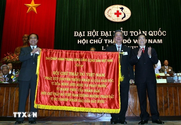 Chủ tịch nước Nguyễn Minh Triết trao tặng bức trướng của Ban chấp hành Trung ương Đảng cho Hội Chữ thập Đỏ Việt Nam tại Đại hội đại biểu toàn quốc Hội Chữ thập Đỏ Việt Nam lần thứ VIII (29/6/2007). (Ảnh: Nguyễn Khang/TTXVN)