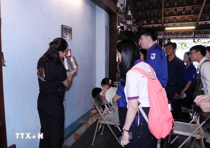 Các lưu học sinh Lào, Campuchia nghe giới thiệu về ngăn chứa bí mật của lực lượng Biệt động Sài Gòn giấu trong tường. (Ảnh: Xuân Khu/TTXVN)