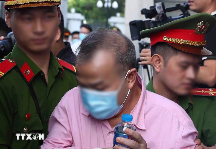Lực lượng chức năng dẫn giải bị cáo Vũ Hồng Nam, cựu Đại sứ Việt Nam tại Nhật Bản, cựu Thứ trưởng Bộ Ngoại giao, tới phiên tòa xét xử. (Ảnh: Phạm Kiên/TTXVN)
