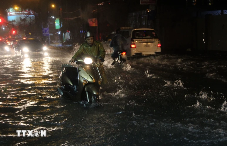 Nước ngập sâu khiến nhiều xe bị chết máy phải dắt bộ. (Ảnh: Xuân Dự/TTXVN)