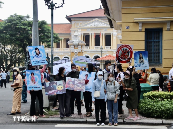 Rất đông người dân trong và ngoài Thành phố Hồ Chí Minh căng biểu ngữ ủng hộ người bị hại và theo dõi vụ án bên ngoài phiên tòa. (Ảnh: Thanh Vũ/TTXVN) 