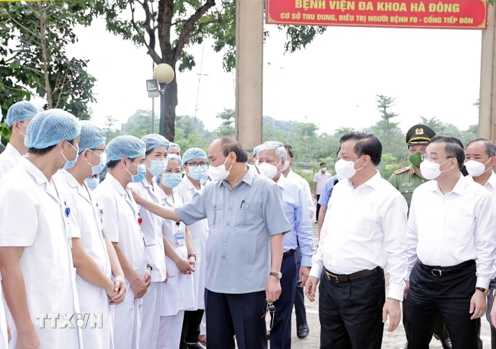 Chủ tịch nước Nguyễn Xuân Phúc động viên các nhân viên ý tế làm việc tại cơ sở thu dung, điều trị bệnh nhân mắc COVID-19 do Bệnh viện Đa khoa Hà Đông điều hành. (Ảnh: Thống Nhất/TTXVN) 