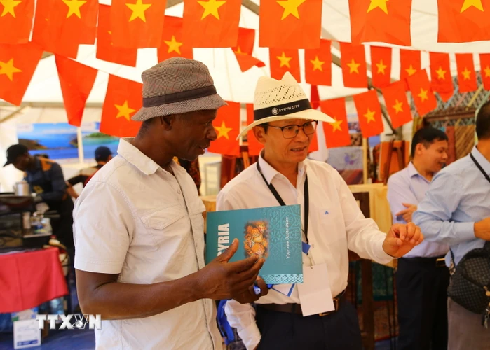 Đại sứ Việt Nam tại Nam Phi Hoàng Văn Lợi (phải) giới thiệu với bạn bè quốc tế về văn hóa và ẩm thực Việt Nam tại Hội chợ Ngoại giao Nam Phi 2022. (Ảnh: Hồng Minh/TTXVN)