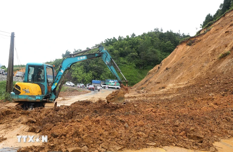 Máy xúc dọn lượng đất đá sạt ra đường để đảm bảo an toàn giao thông tại tỉnh Lào Cai. (Ảnh: Quốc Khánh/TTXVN)