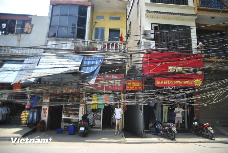 Đã 3 ngày nay, những người dân sống trên phố Hoàng Hoa Thám (quận Ba Đình, Hà Nội) phải quen với khung cảnh dây điện chằng chịt căng trước cửa nhà. (Ảnh: Võ Phương/Vietnam+)