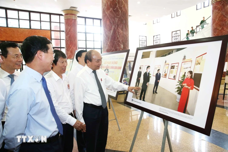 Thủ tướng Chính phủ Nguyễn Xuân Phúc và các đại biểu tham quan trưng bày ảnh 'Việt Nam phòng, chống dịch COVID-19.' (Ảnh: Phương Hoa/TTXVN) 