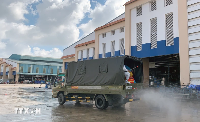 Lực lượng chức năng triển khai phun thuốc khử khuẩn tại khuôn viên bên ngoài lồng chợ Bình Điền. (Ảnh: TTXVN phát)