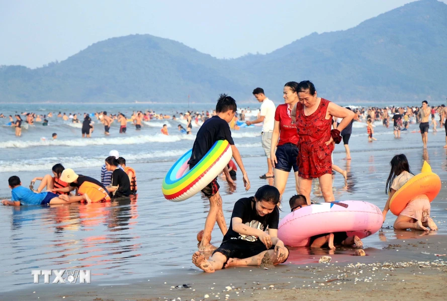Du khách giải nhiệt trên bãi biển Xuân Hải huyện Lộc Hà, Hà Tĩnh. (Ảnh: Công Tường/TTXVN)