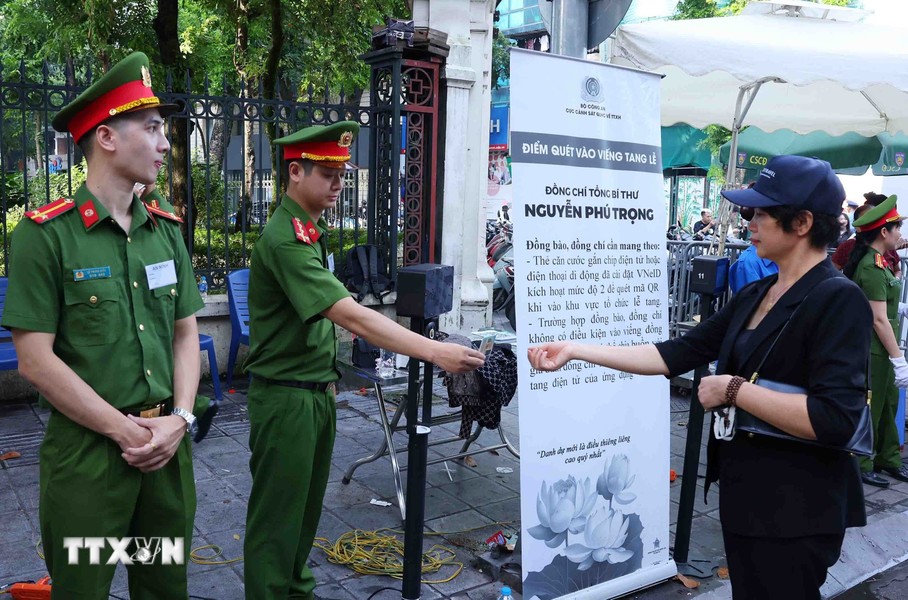 Lực lượng công an hỗ trợ người dân quét xác thực thẻ CCCD để vào viếng Tổng Bí thư Nguyễn Phú Trọng tại Nhà tang lễ Quốc gia, sáng 26/7 (Ảnh: TTXVN)