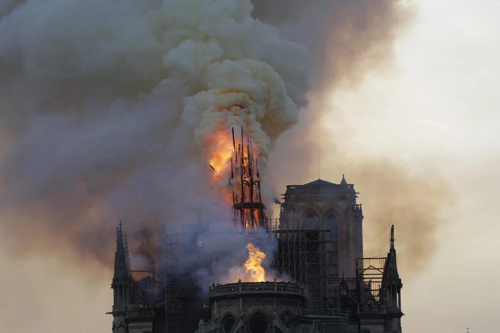 Tháp chuông bị sập khi lửa khói bao trùm nóc Nhà thờ Đức Bà ở Paris, Pháp. (Ảnh: AFP/TTXVN)