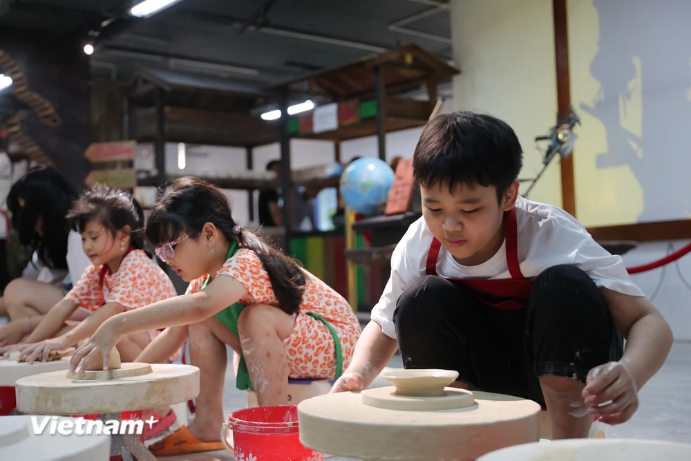 Các em nhỏ trong dịp nghỉ Hè được trải nghiệm thực tế làm sản phẩm gốm tại Bát Tràng. (Ảnh: Hoài Nam/Vietnam+)