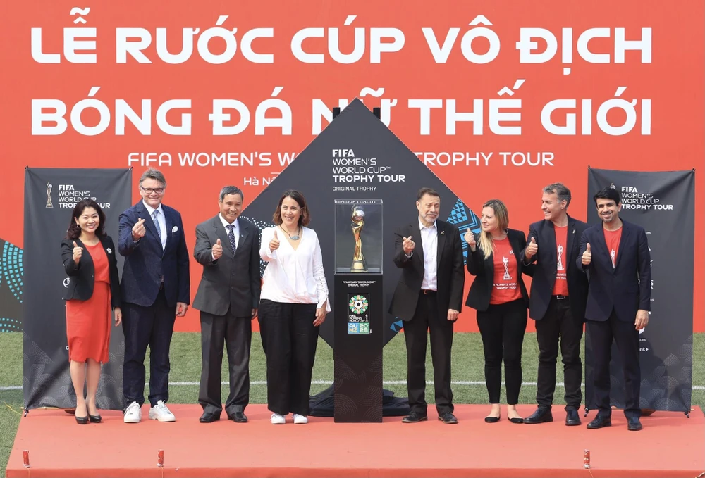 Huấn luyện viên Mai Đức Chung cùng Philippe Troussier chụp ảnh với đại diện FIFA và cúp vô địch World Cup nữ 2023. (Ảnh: PV/Vietnam+)