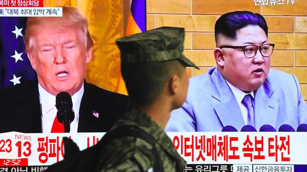 Một binh sỹ Hàn Quốc đi ngang qua màn hình chiếu hình Tổng thống Donald Trump và nhà lãnh đạo Triều Tiên Kim Jong Un. (Ảnh: AFP)