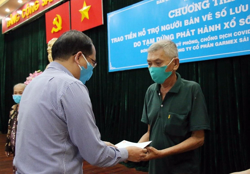 Chủ tịch UBND huyện Hóc Môn trao tiền hỗ trợ cho người bán vé số trên địa bàn. (Ảnh: Tiến Lực/TTXVN)