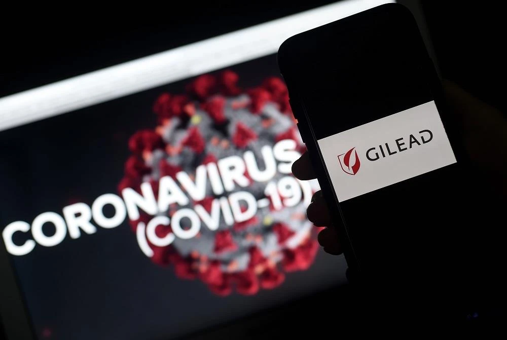 Biểu tượng của công ty công nghệ sinh học Gilead (Mỹ) và hình ảnh đồ họa mô phỏng virus SARS-CoV-2 gây dịch COVID-19. (Ảnh: AFP/TTXVN)