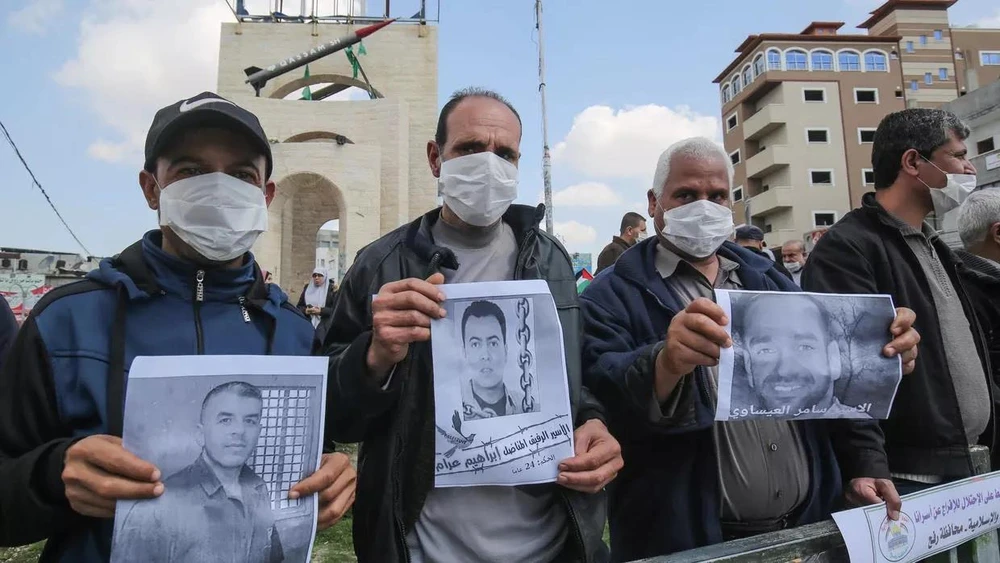 Người dân Palestine cầm bức ảnh của các tù nhân bị Israel bắt giữ. (Nguồn: AFP)
