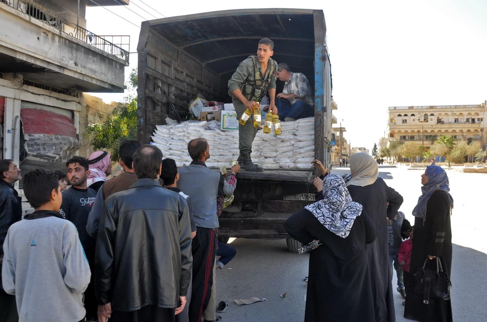Người dân xếp hàng nhận nhu yếu phẩm cứu trợ tại Al-Qaryatain, Syria. (Ảnh: AFP/TTXVN)