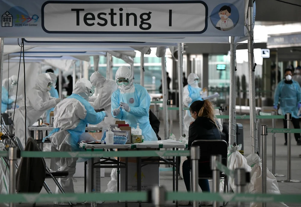 Nhân viên y tế lấy mẫu dịch xét nghiệm COVID-19 cho hành khách tại sân bay quốc tế Incheon, phía tây thủ đô Seoul, Hàn Quốc, ngày 1/4/2020. (Ảnh: AFP/TTXVN)