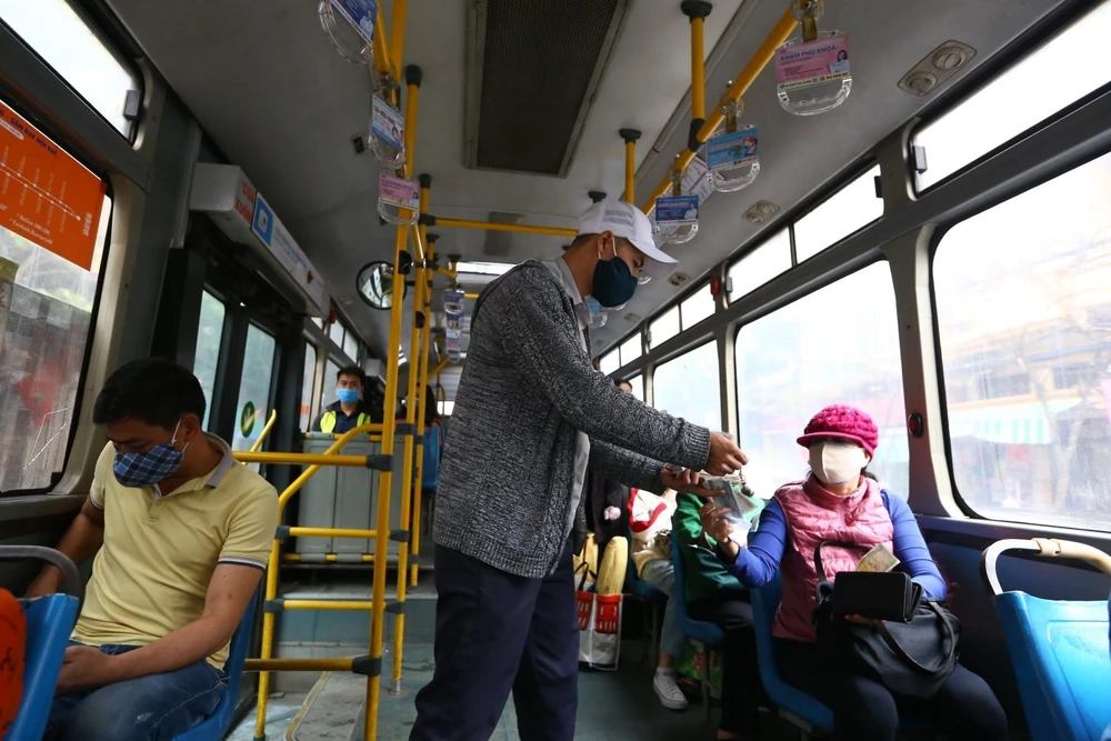 Hành khách thực hiện đeo khẩu trang khi tham gia giao thông trên xe buýt công cộng. (Ảnh: Minh Quyết/TTXVN)