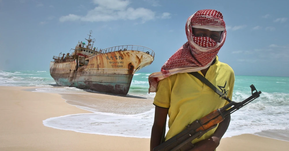 Cướp biển Somalia đứng cạnh một con tàu bị bắt. (Nguồn: AP)