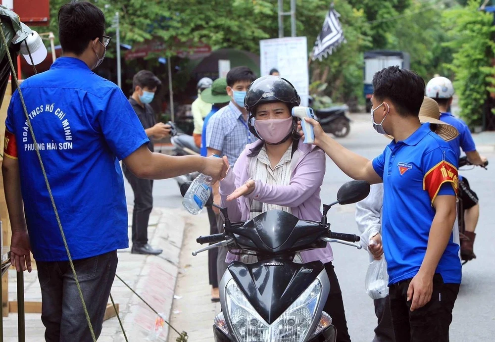 Lực lượng đoàn thanh niên quận Đồ Sơn, Hải Phòng kiểm tra thân nhiệt, phun dung dịch sát khuẩn tay tại chốt kiểm soát dịch COVID-19. (Ảnh: An Đăng/TTXVN)