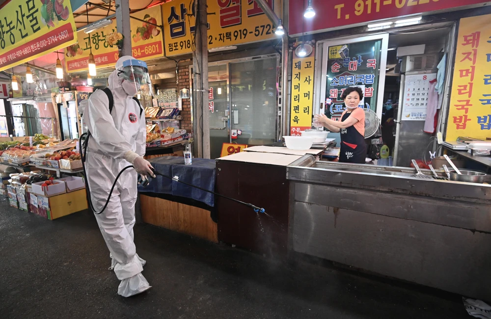 Phun thuốc khử trùng nhằm ngăn chặn sự lây lan của dịch COVID-19 tại một khu chợ ở Seoul, Hàn Quốc ngày 18/8/2020. (Ảnh: AFP/TTXVN)